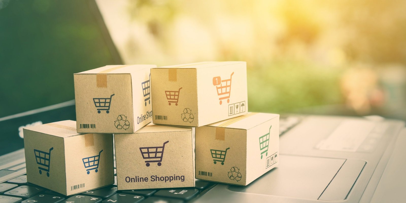 Online shopping / ecommerce and delivery service concept : Paper cartons with a shopping cart or trolley logo on a laptop keyboard, depicts customers order things from retailer sites via the internet.