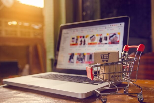 Shopping online. Parcel or cardboard boxes with a shopping cart logo in a trolley on a laptop keyboard. Shopping service on The online web. offers home delivery.